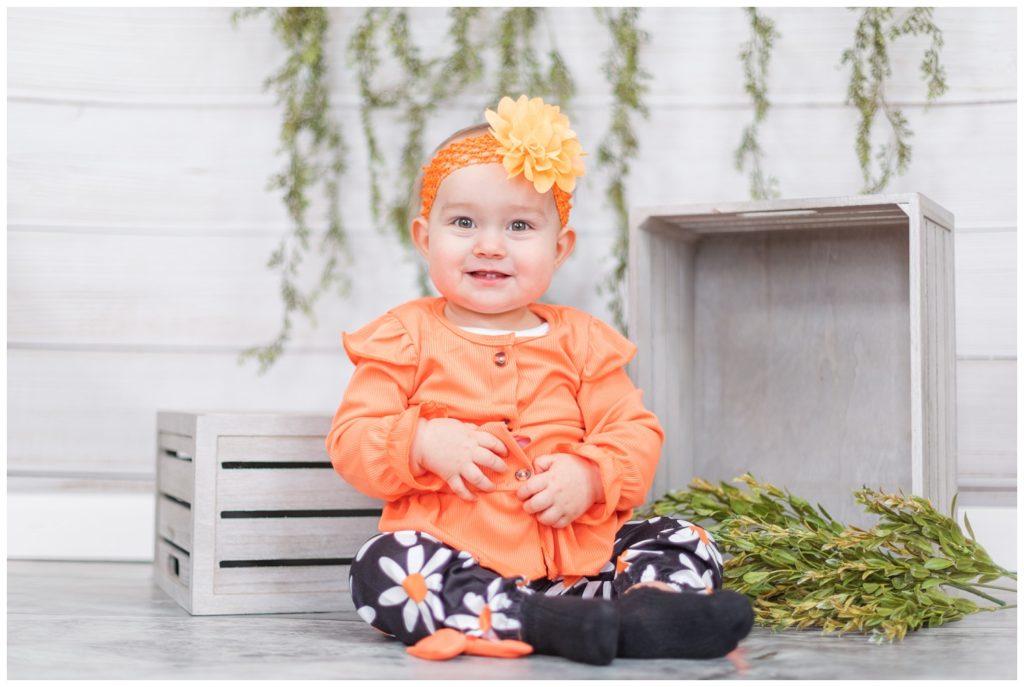 baby sitting in a studio wearing an orange and black outfit