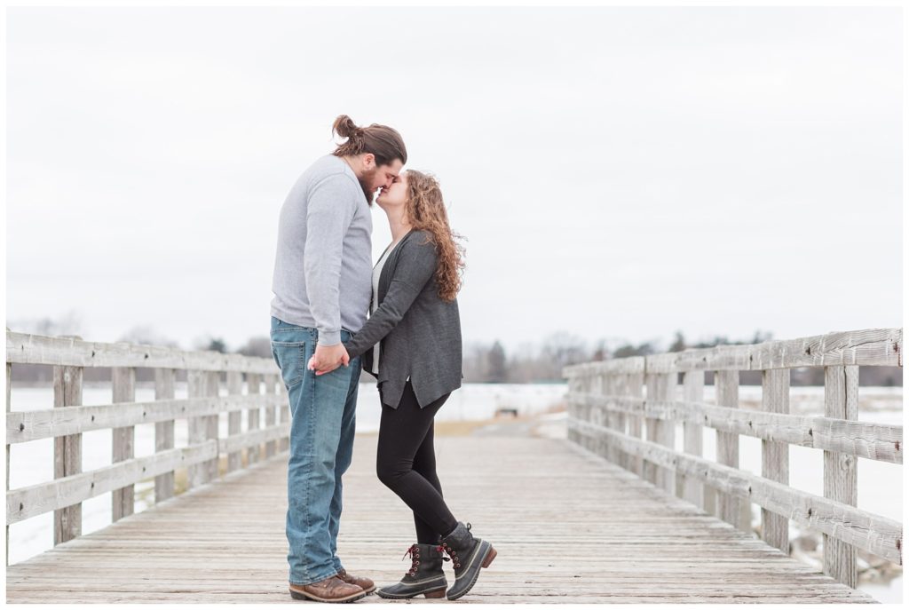 couple standing on a deck touching noses during engagement session