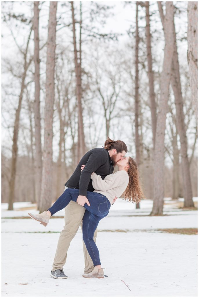 man dipping back fiance in front of trees and snow in Ohio