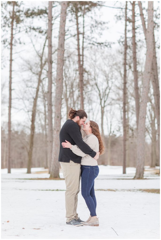 couple holding each other in snow in front of trees in Ohio