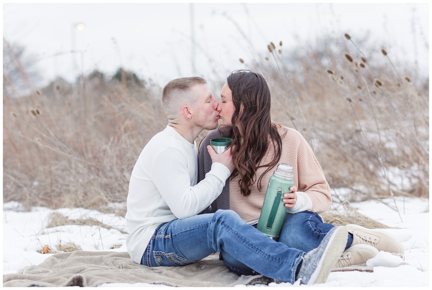 couple sitting and drinking coffee and kissing for engagement photos