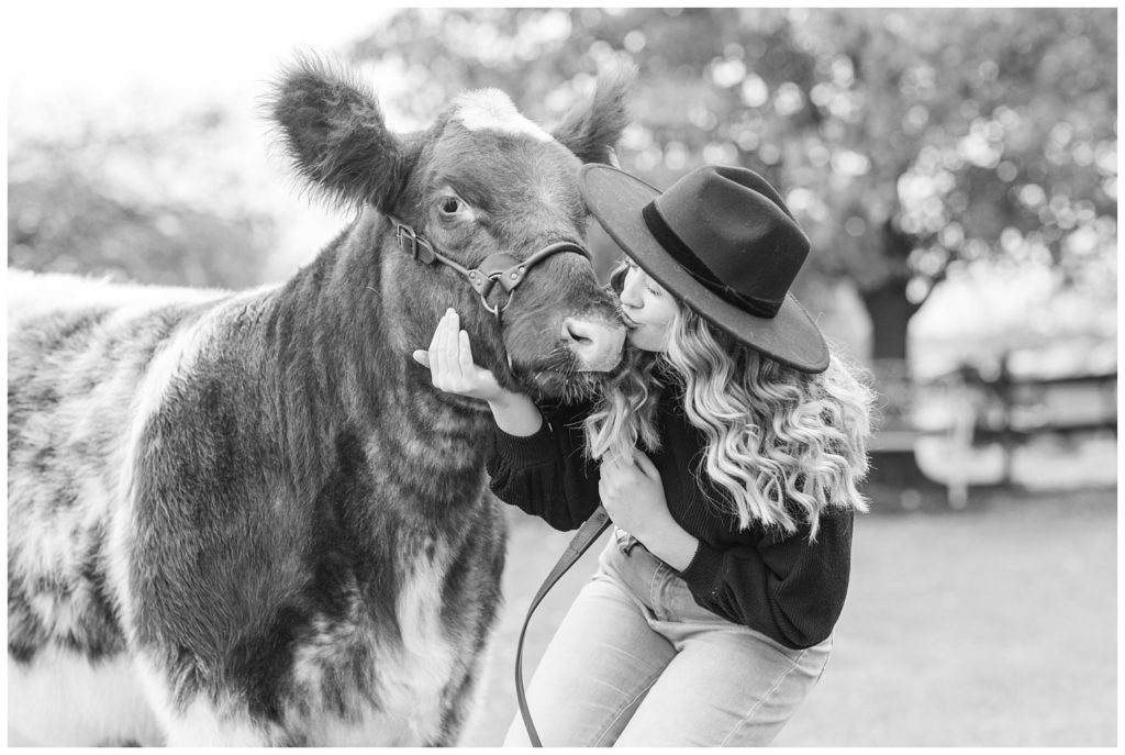 senior girl kissing her cow on her farm