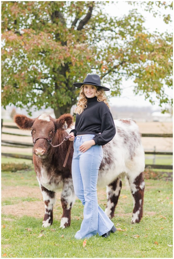 girl posing with her cow outside for her senior photos