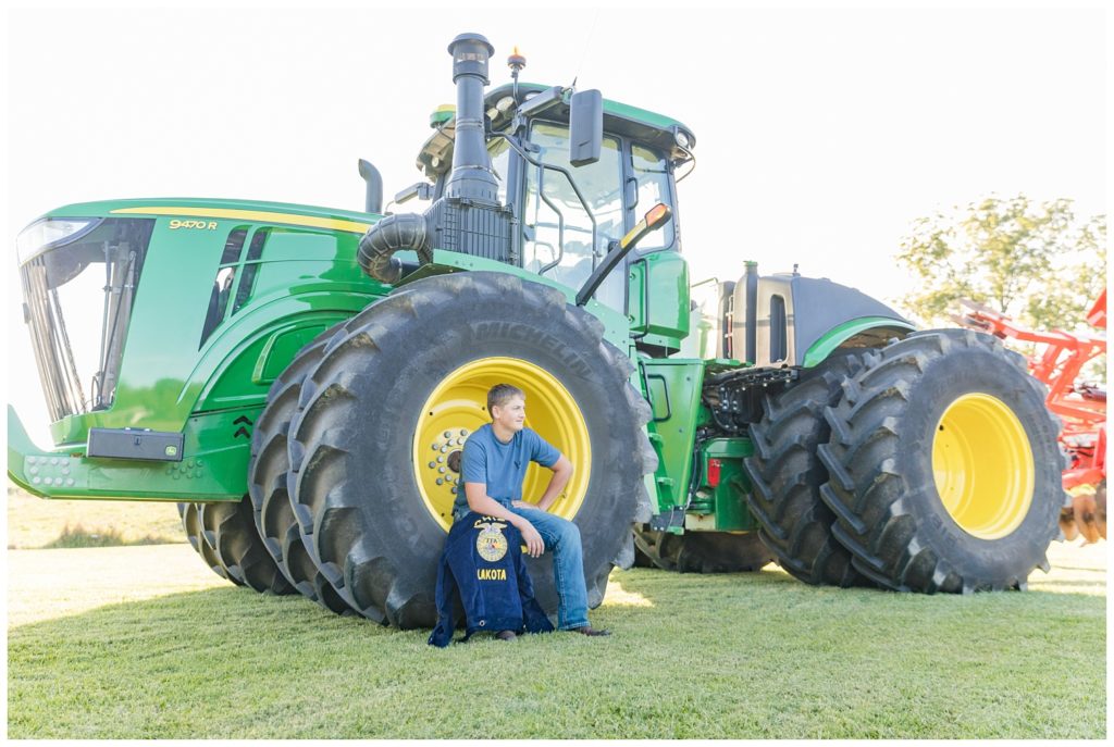boy sitting on a tractor for his senior photos in Ohio