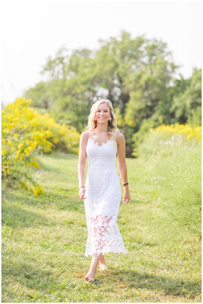 girl wearing a white dress walking barefoot in a field