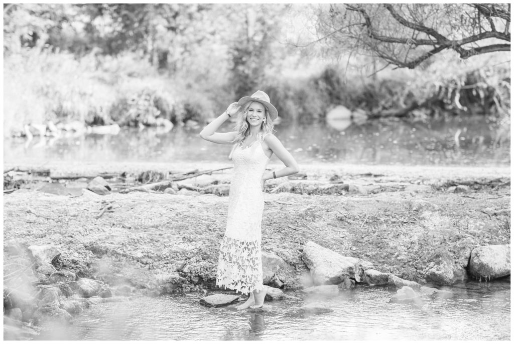 black and white photo of senior girl posing in a creek in Ohio