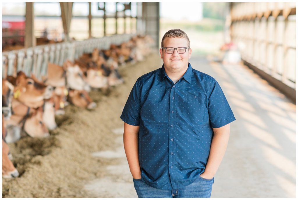 boy posing in front of his cows in Ohio for senior photos