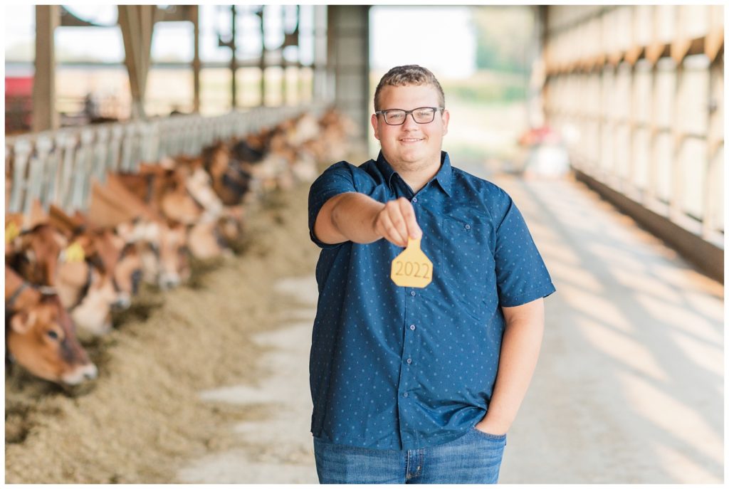 boy holding out his award next to his cows on his family farm in Ohio