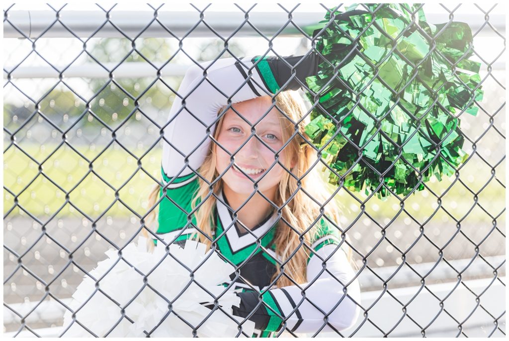 senior cheerleader looking through the fence with her shakers in Ohio