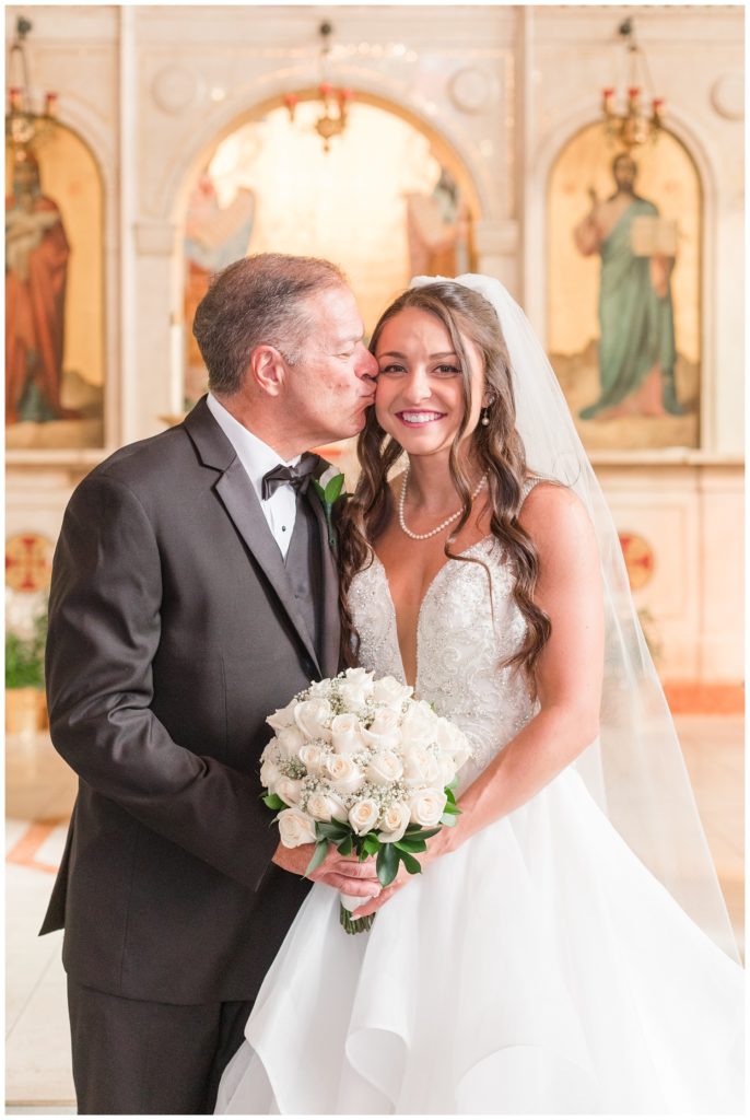 bride's dad kissing bride's cheek at Greek wedding ceremony