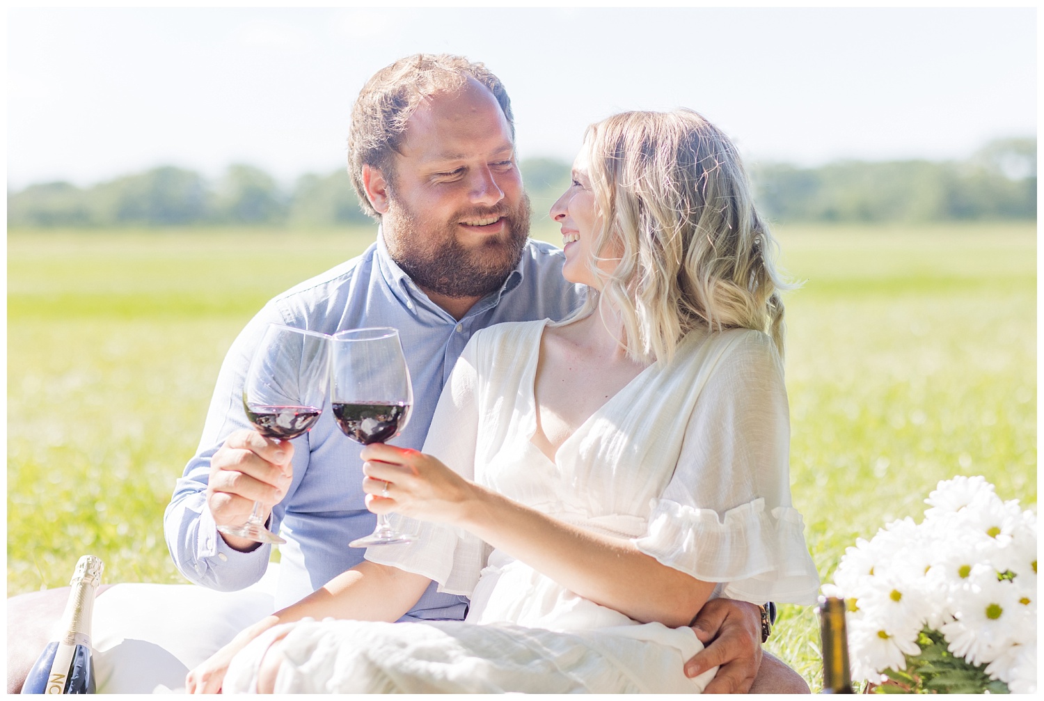 couple toasting with wine during picnic engagement session