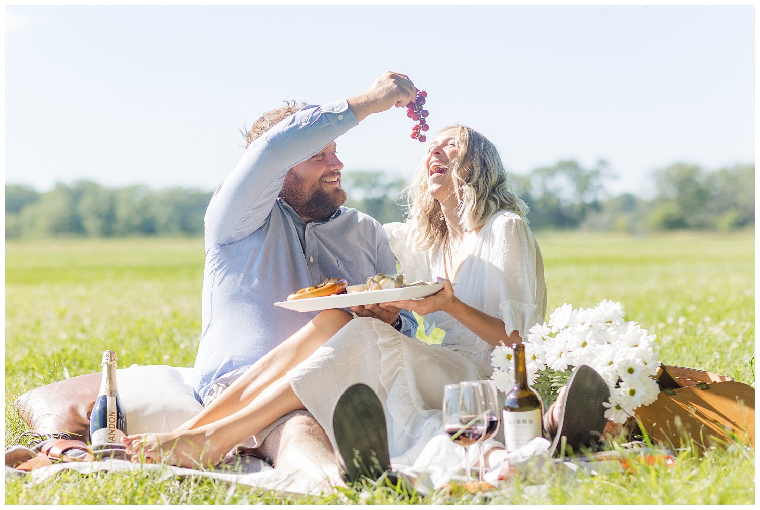 couple eating grapes during picnic engagement session in Ohio