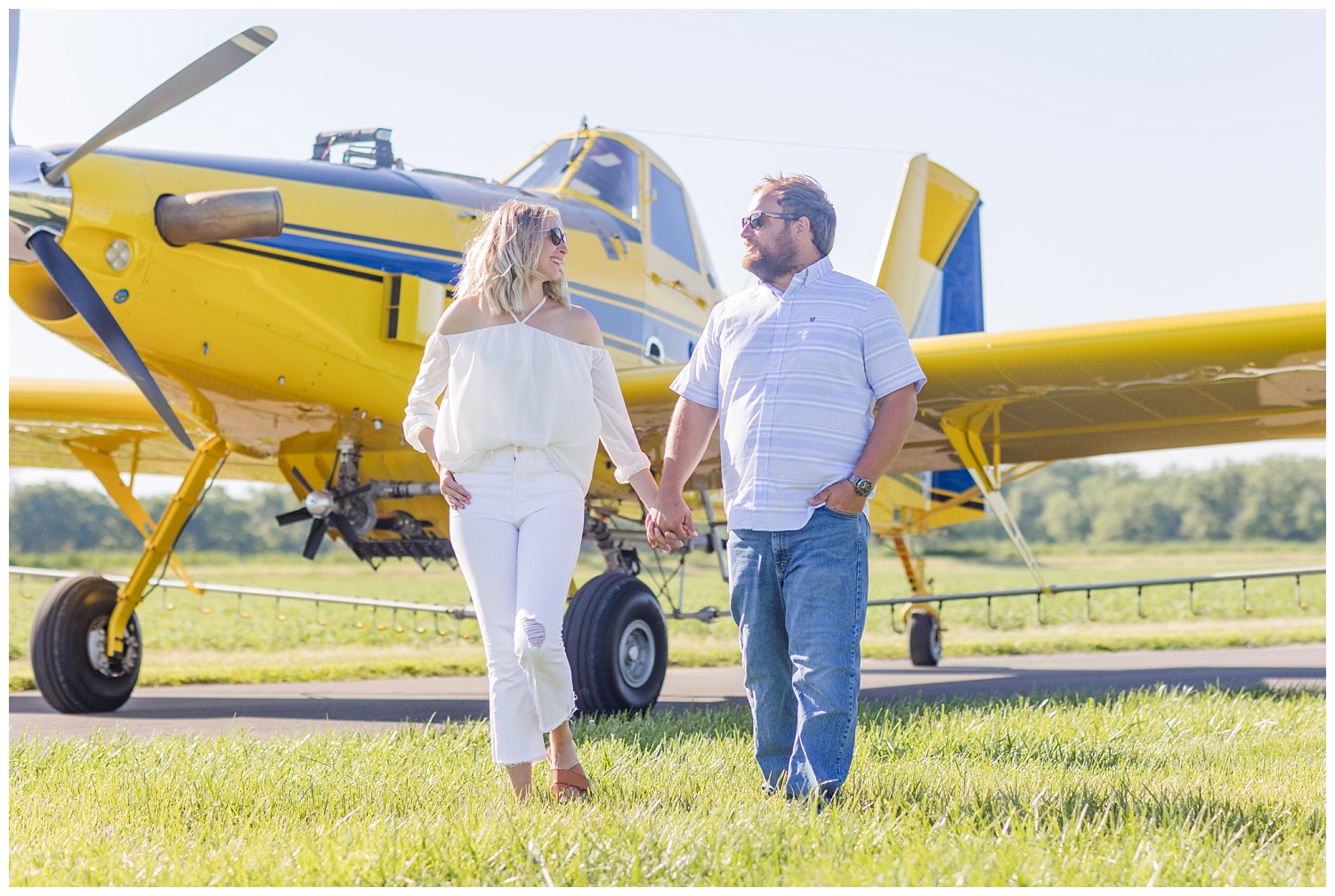 couple walking in front of a yellow airplane wearing sunglasses