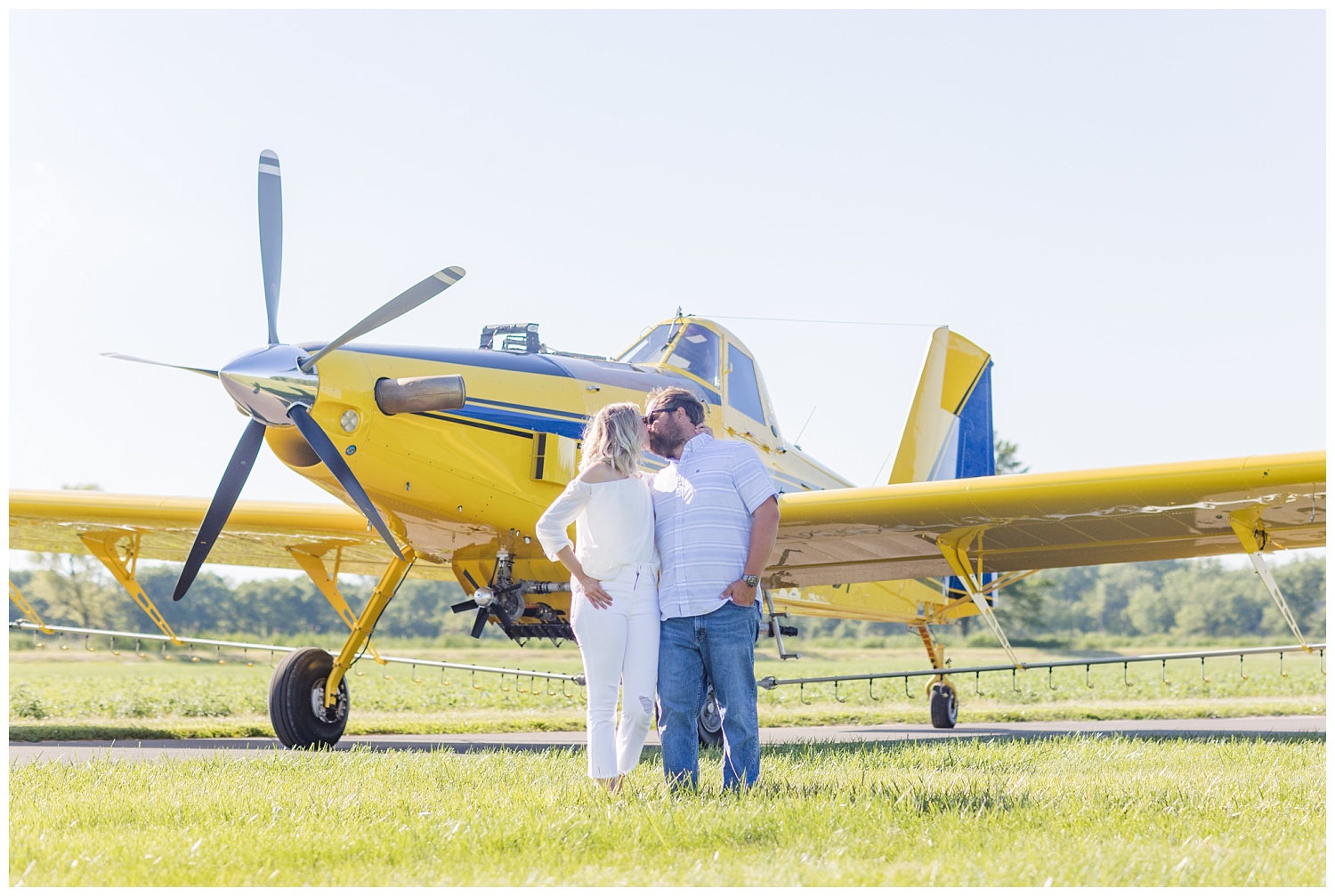 couple kissing in front of a yellow airplane