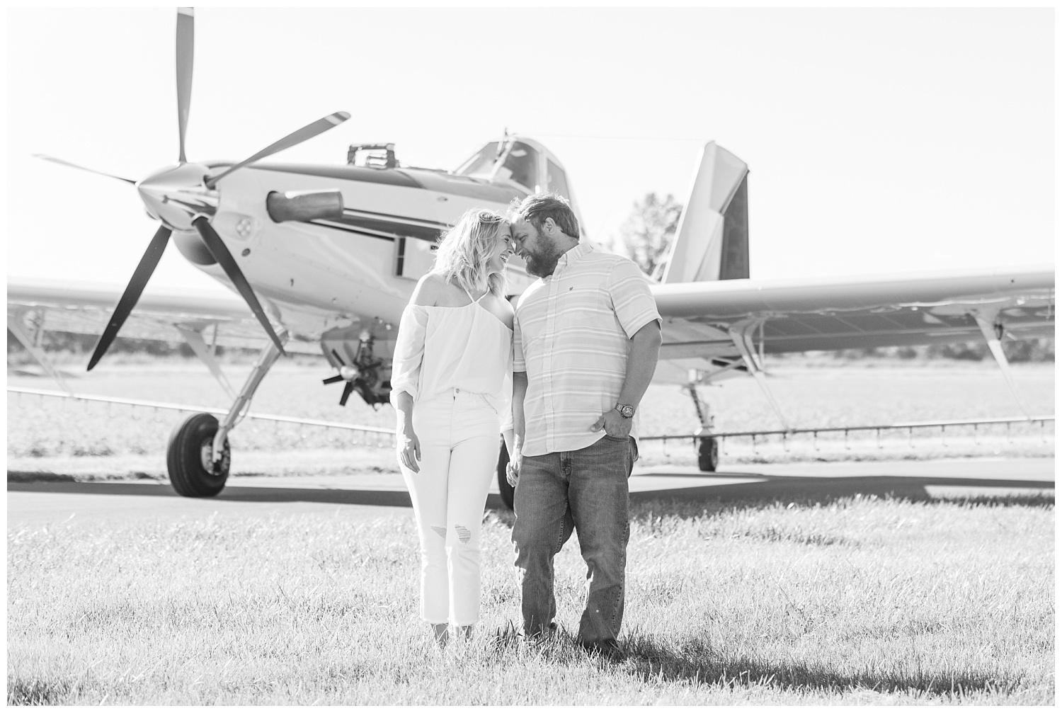 couple touching foreheads in front of an airplane
