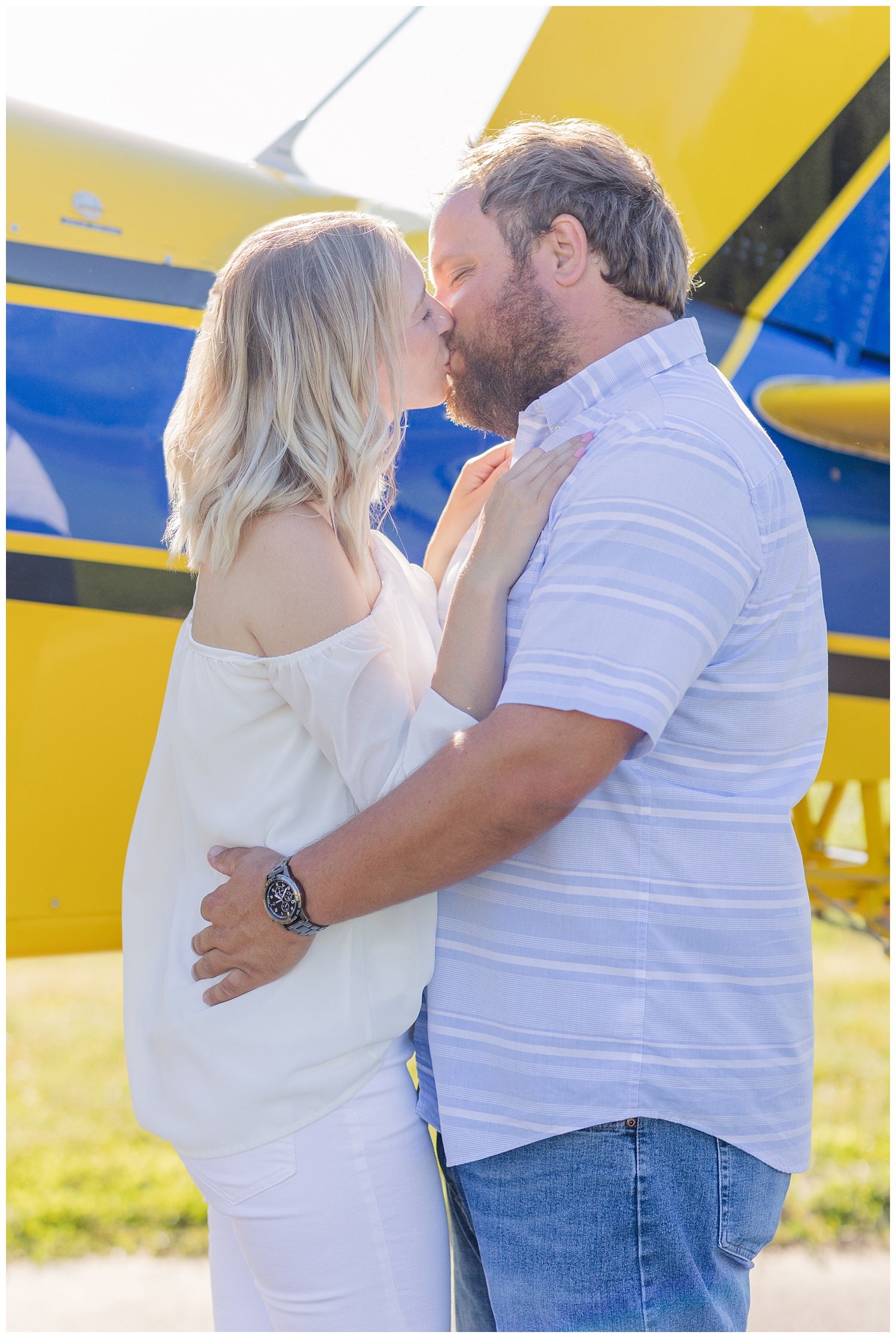 couple kissing in front of a yellow and blue airplane in Fremont, Ohio