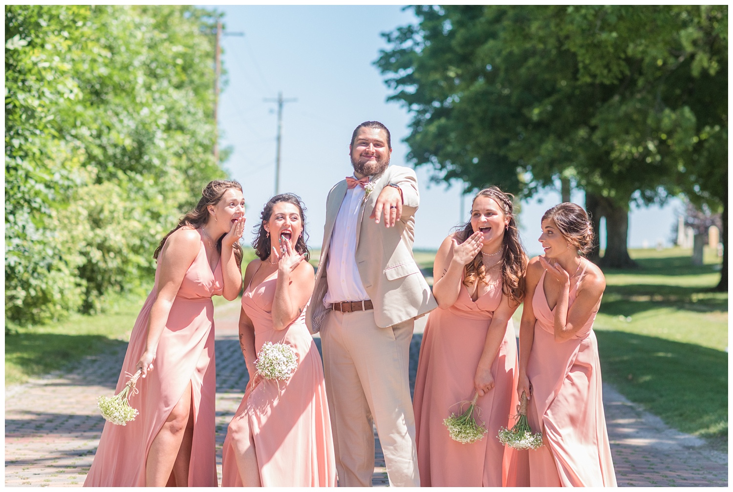 groom posing with bridesmaids outside