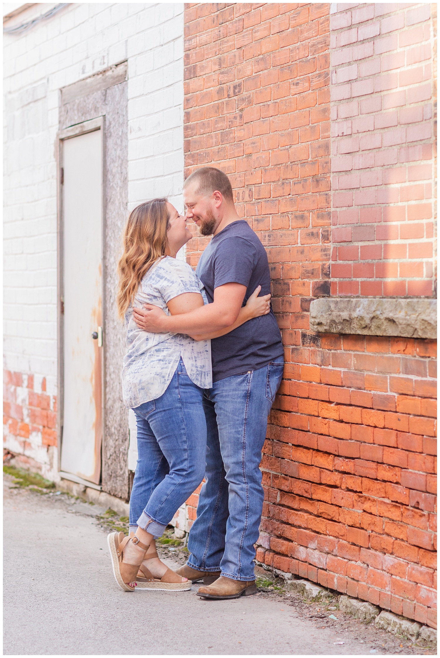 couples touching noses standing against a brick wall 