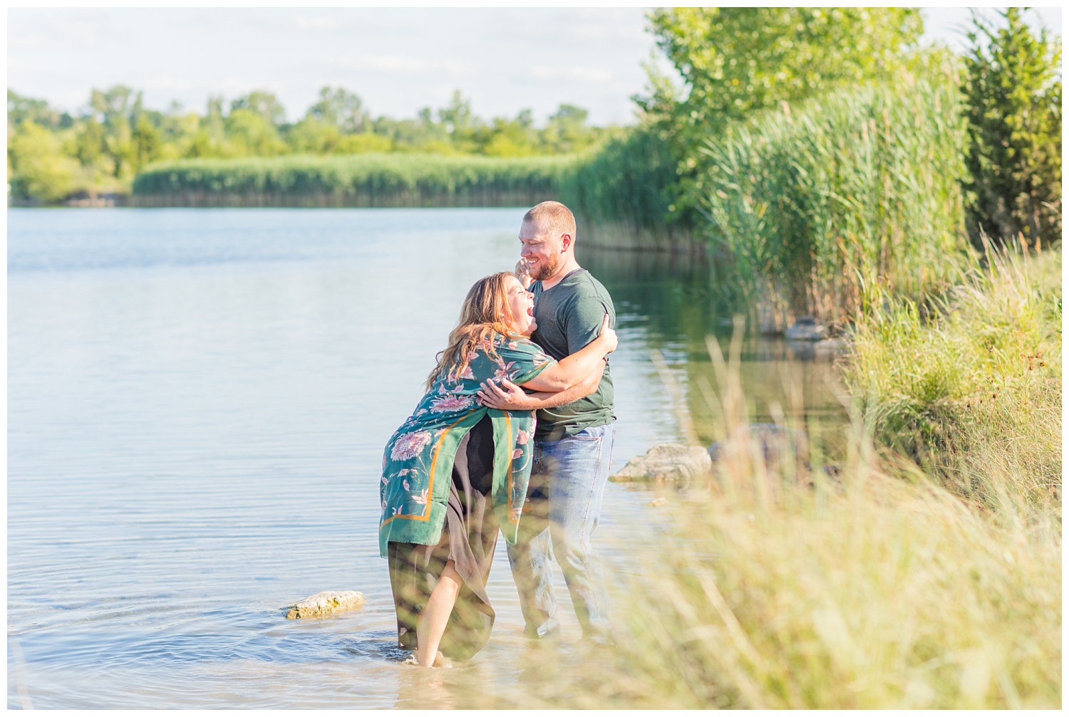 couple laughing while getting their feet wet in the water during engagement session
