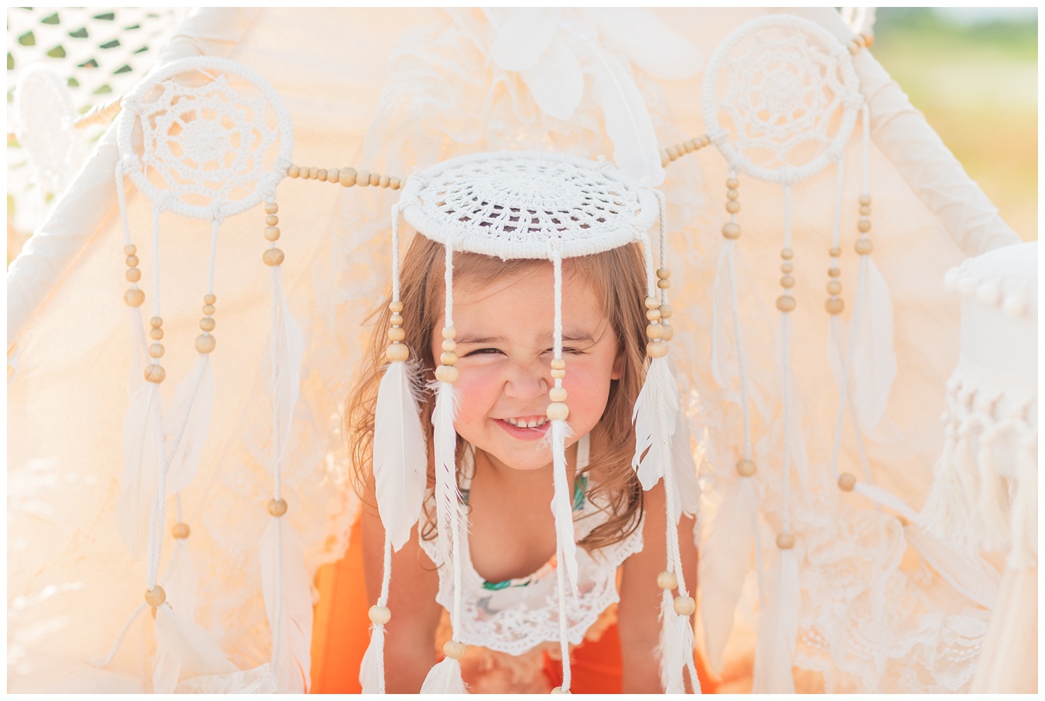 girl placing head under boho props at birthday session
