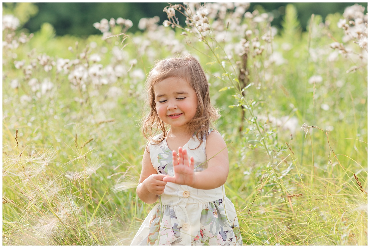 little girl playing with grass in a wheat field