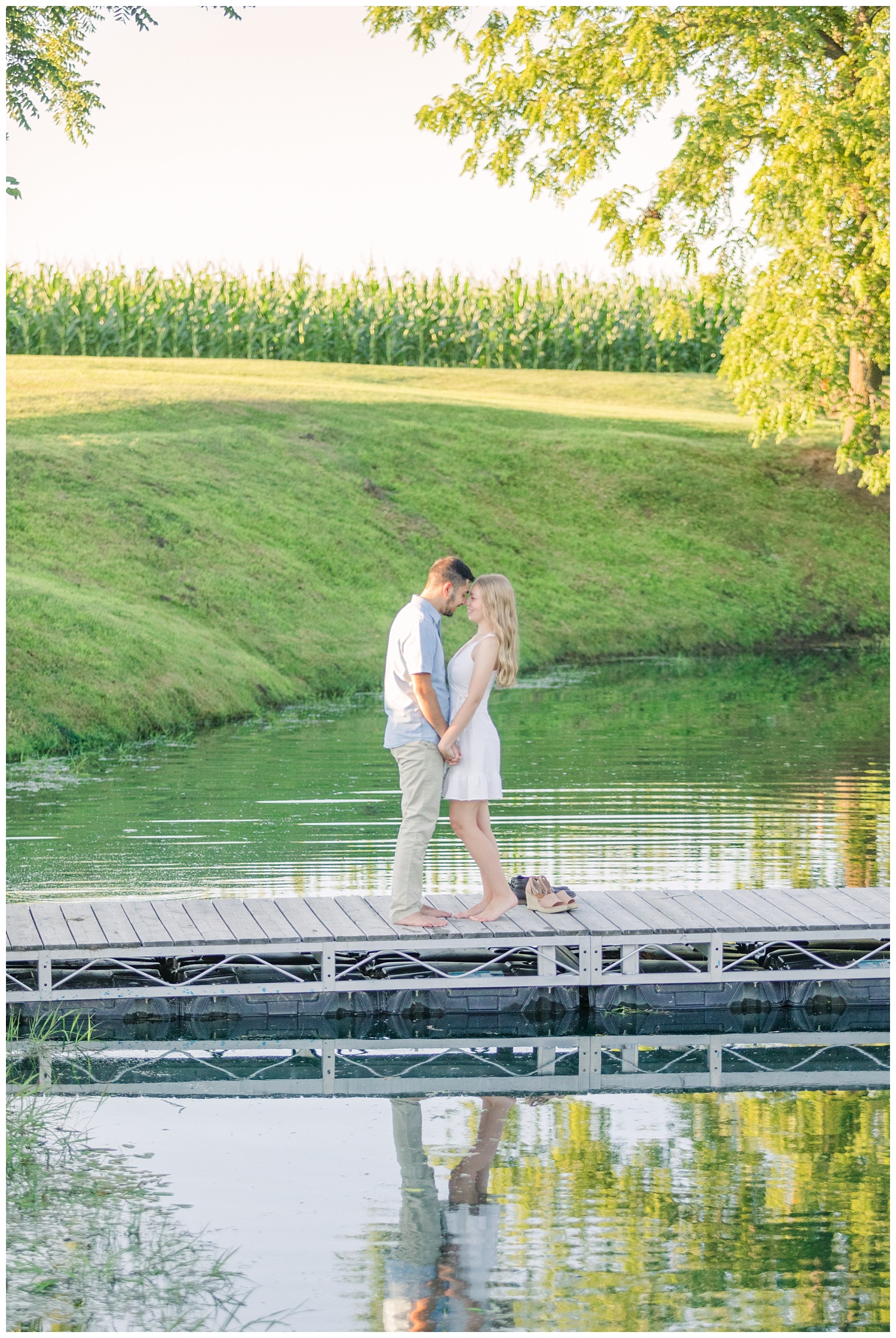 couple standing on a dock barefoot at engagement session