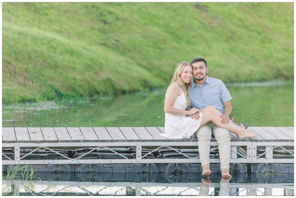 engaged couple sitting on a dock on a pond in Green Springs