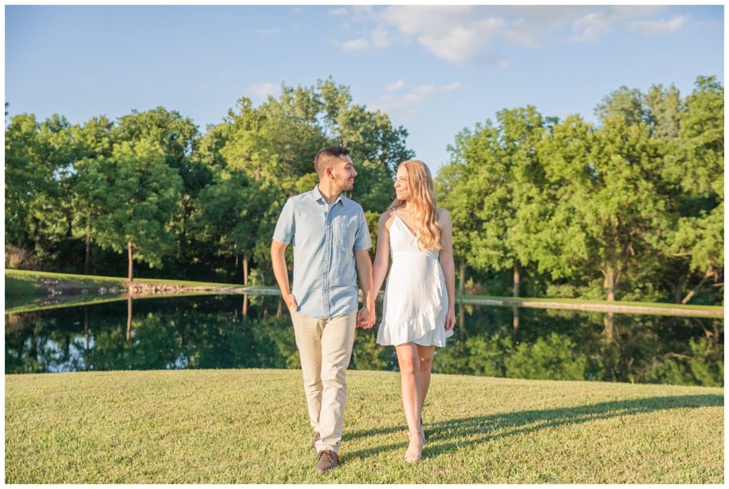 couple walking together next to a pond at engagement session 