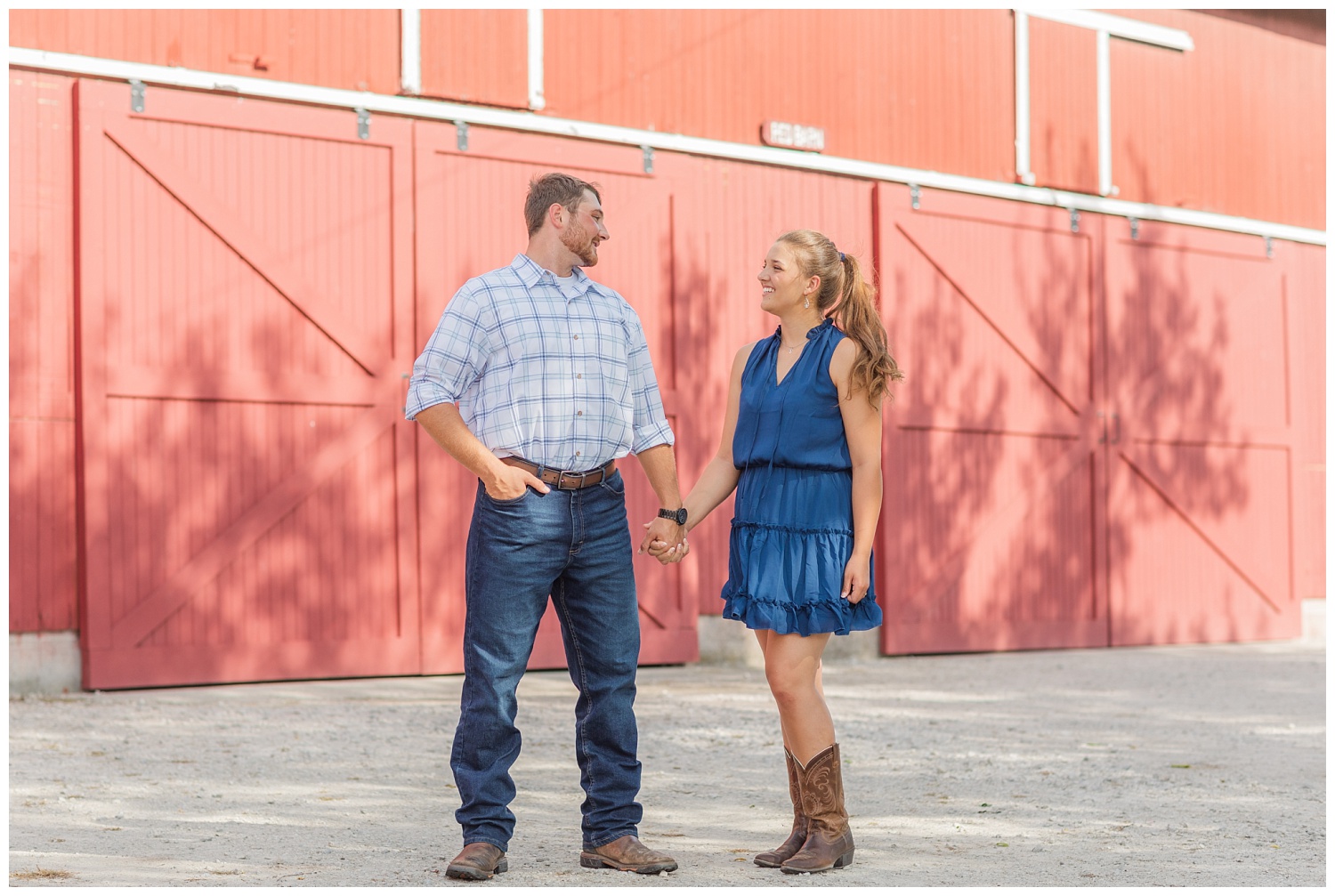 couple holding hands in front of a red barn at Ohio engagement session