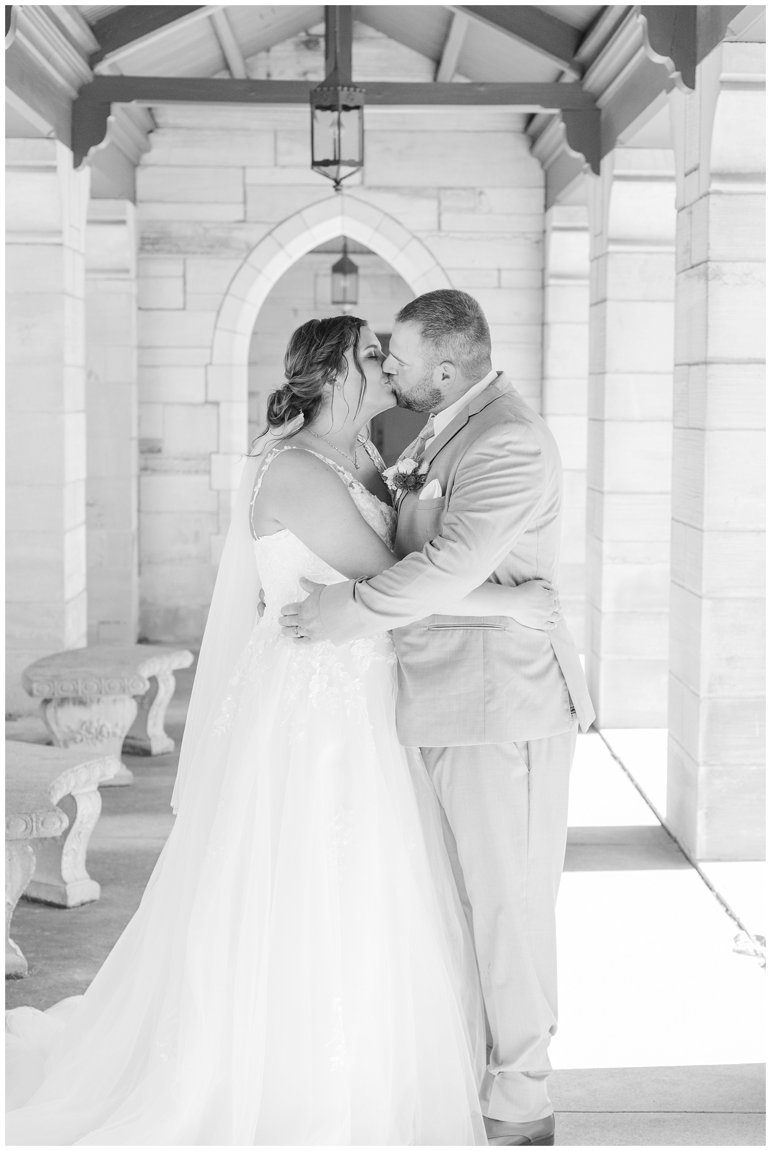 bride and groom kissing under the covered walkway at the church