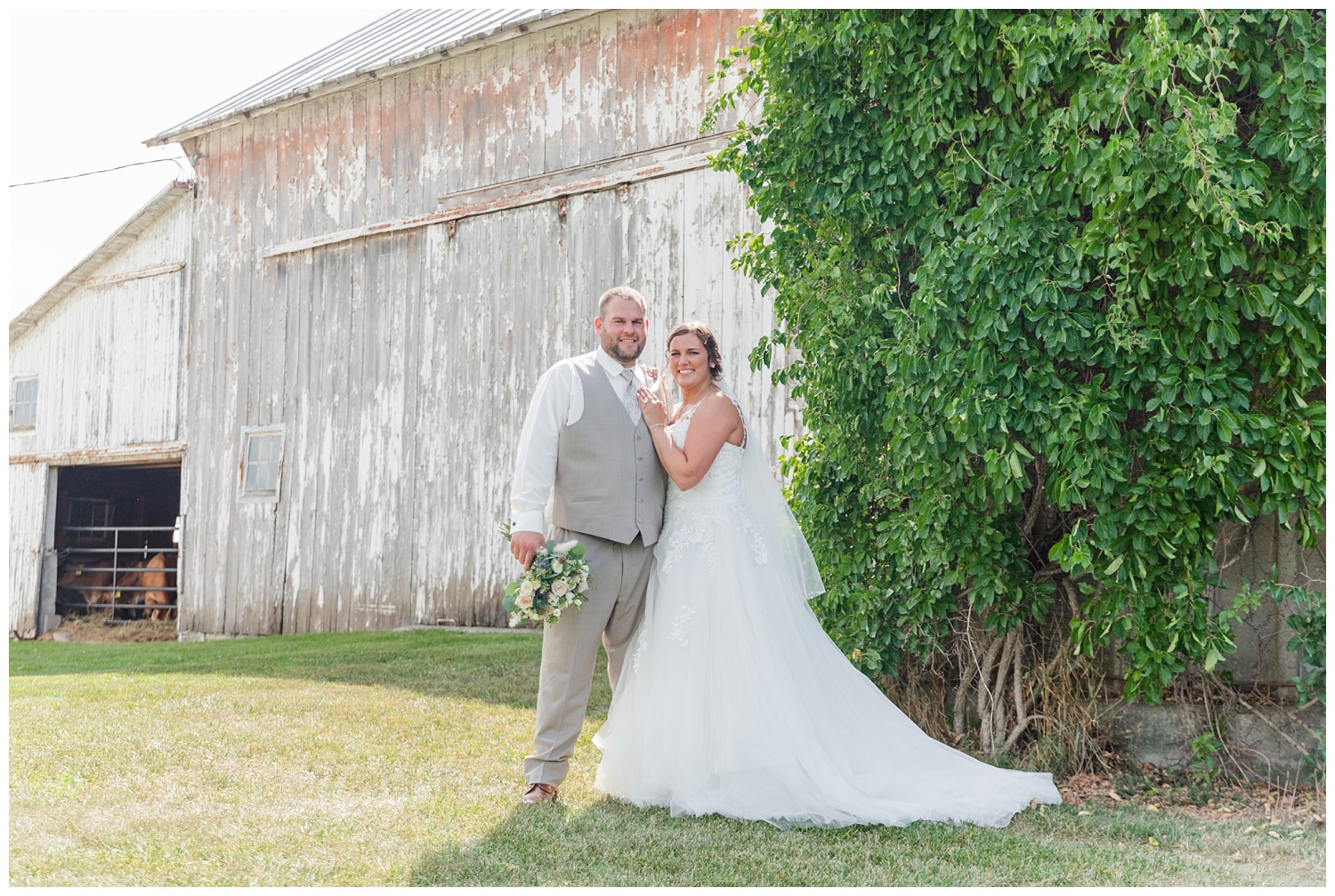 bride and groom posing in front of a white barn in Fremont, Ohio