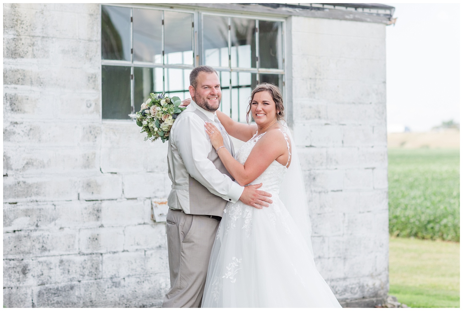 wedding couple posing in front of their white barn in Fremont, Ohio