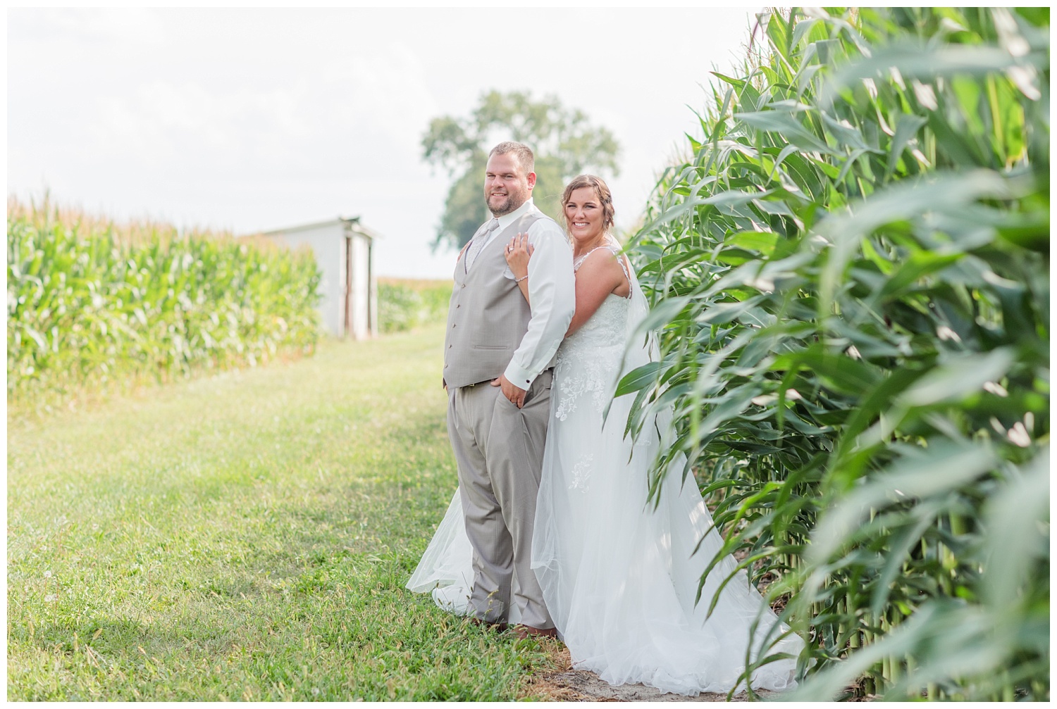 bride and groom posing next to corn stalks