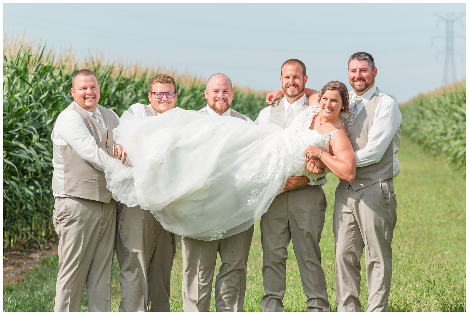 groomsmen holding up the bride in between corn stalks