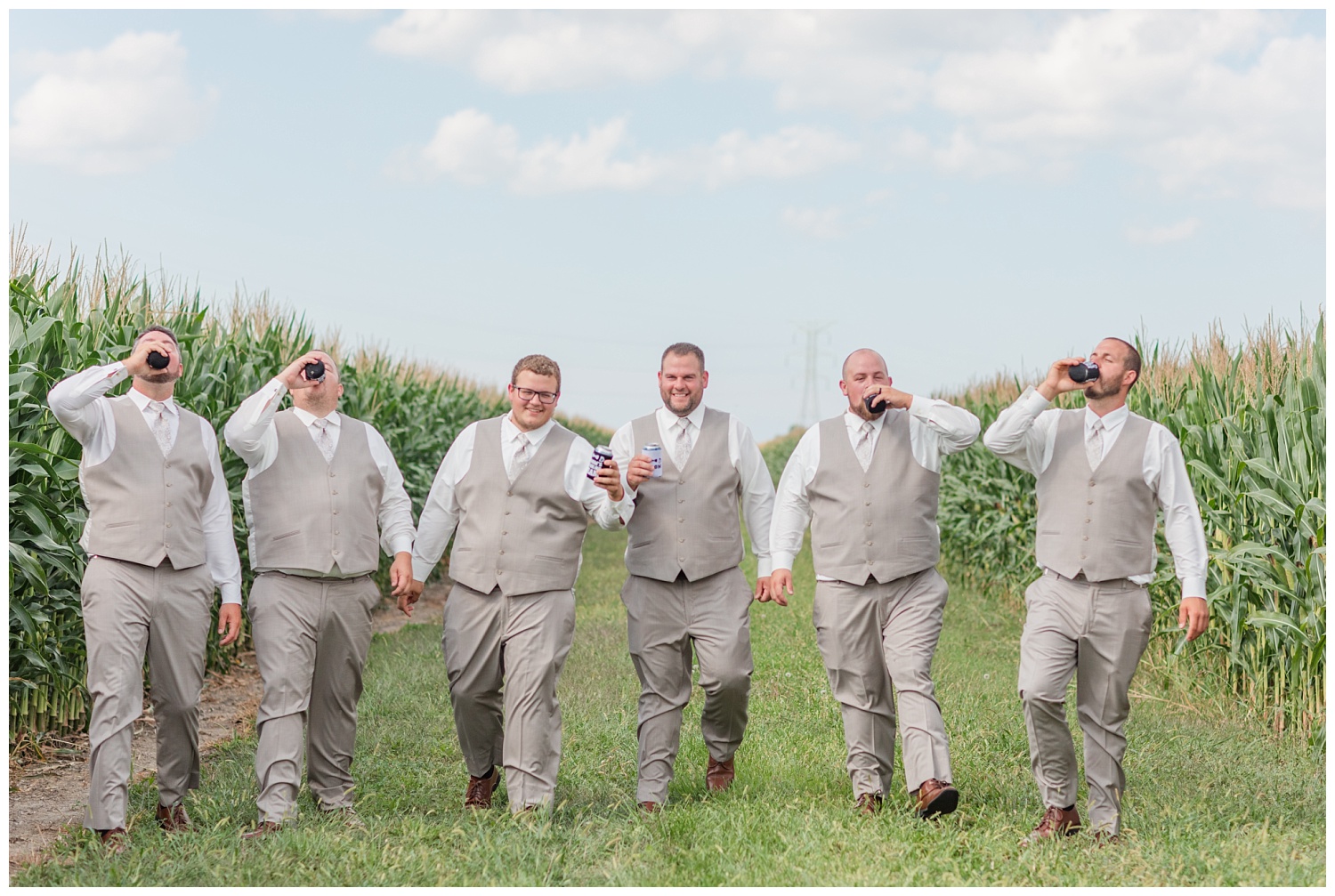groomsmen walking with beers in between the corn stalks