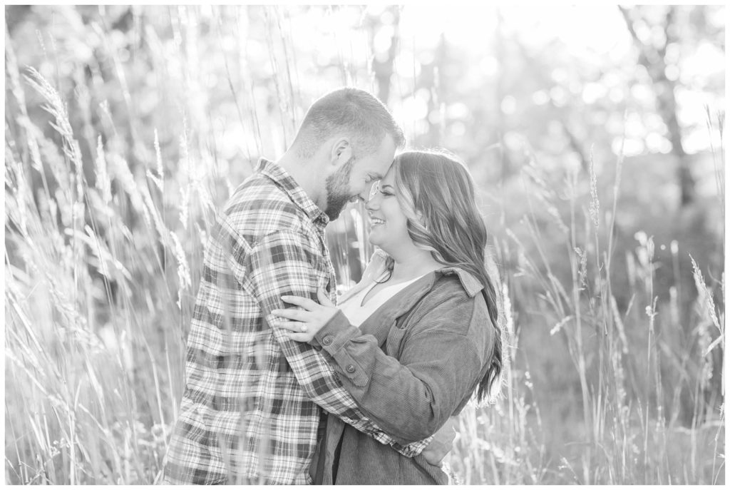 engaged couple touching foreheads in tall grass at Chudzinski Johannsen Park
