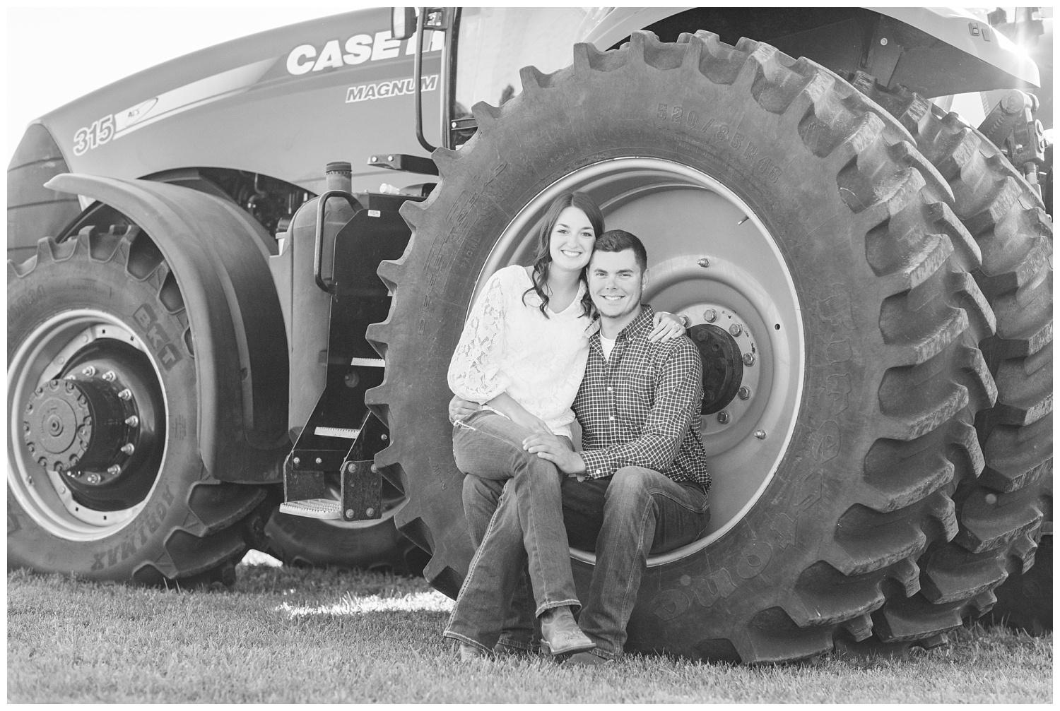 couple sitting on the wheel of a red tractor on a farm
