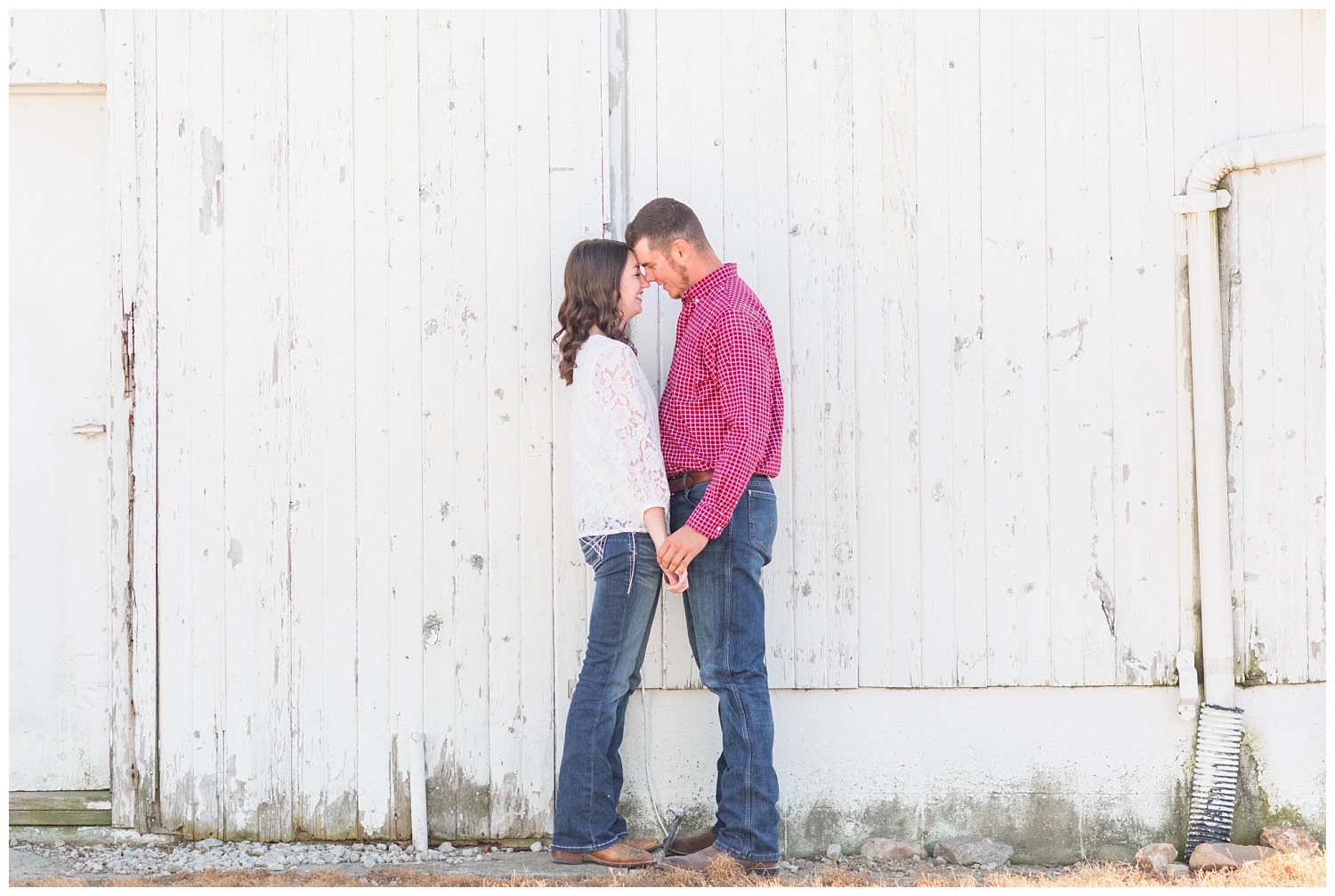 engaged couple standing in front of a white barn in northwest Ohio
