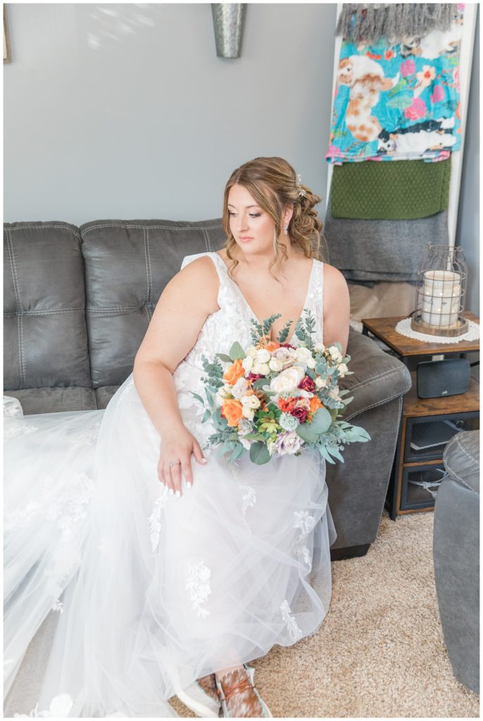 bride sitting with bouquet on a gray couch