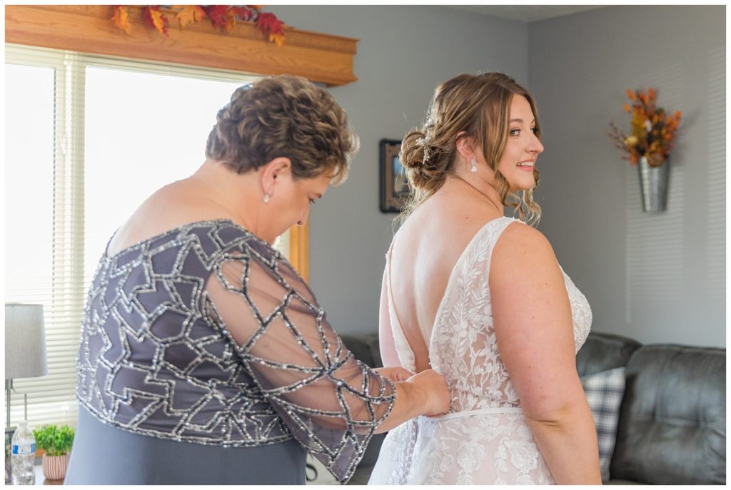 mom zippimg up the bride in her dress in Fostoria, Ohio