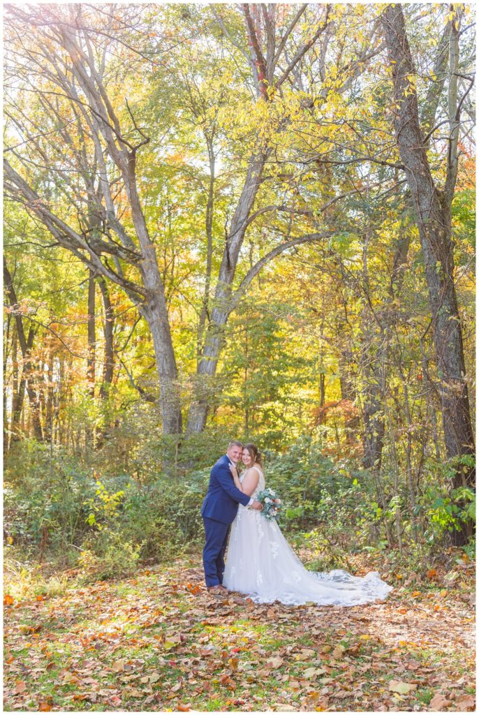 wedding couple posing in front of large trees