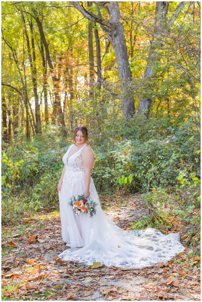bride posing with her bouquet in front of trees