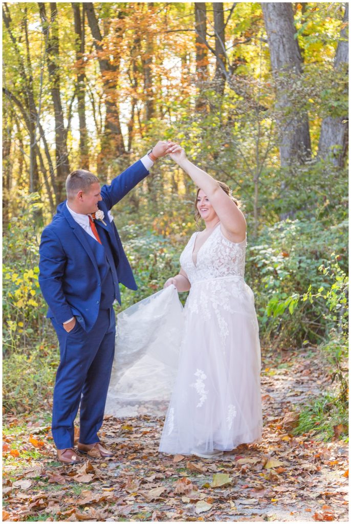 wedding couple twirling in front of trees