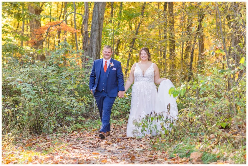 wedding couple walking together and holding hands in the woods