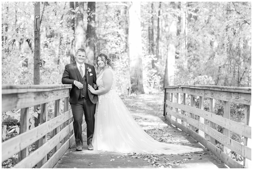 bride and groom posing on a bridge in the woods