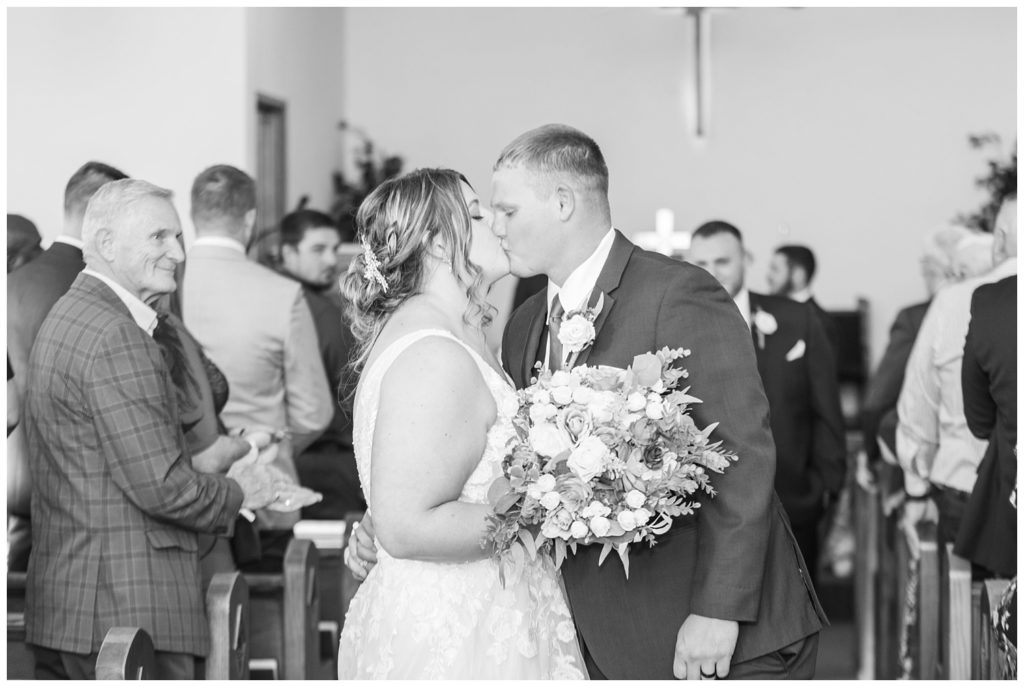 wedding couple kissing at the end of the aisle after ceremony