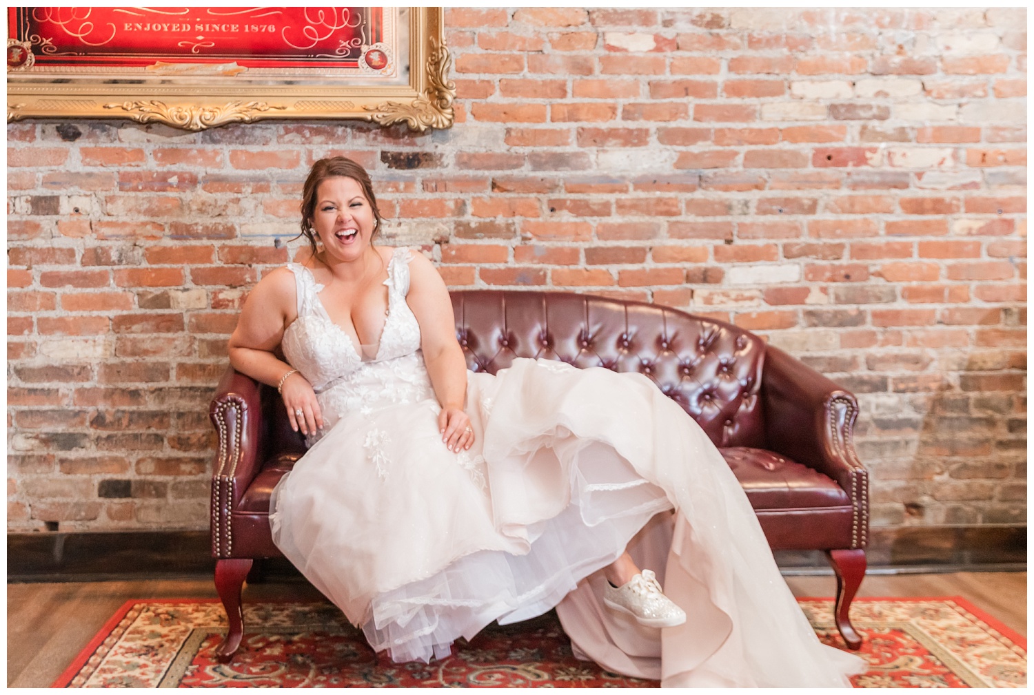 bride laughing on a leather couch at wedding reception