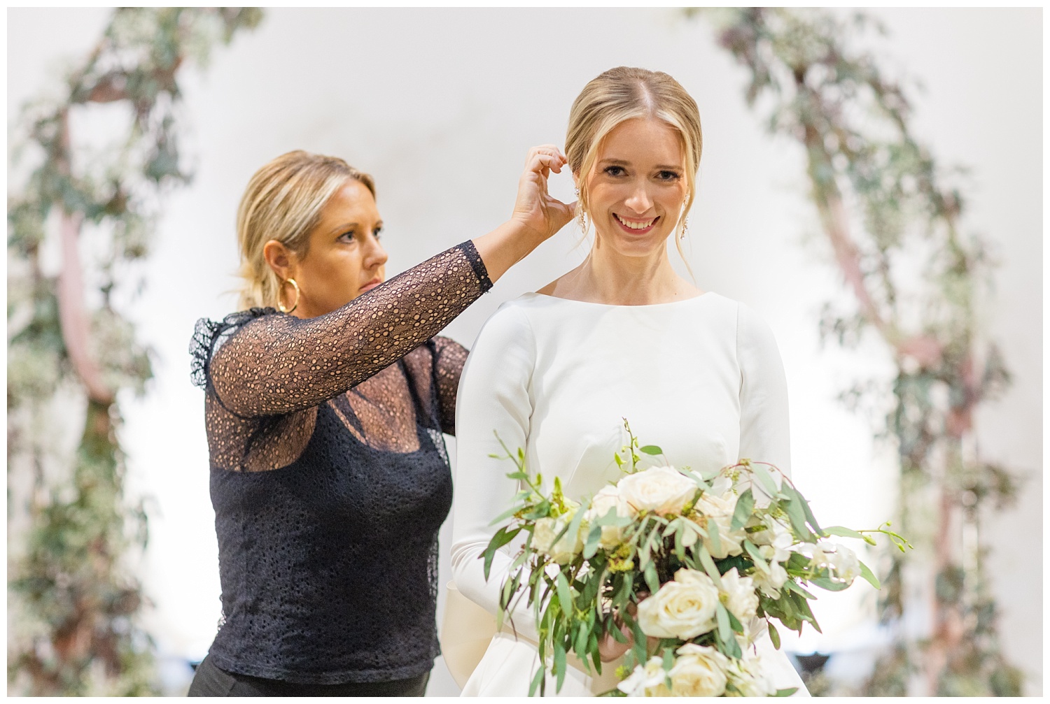 bride holding her bouquet getting her hair adjusted 