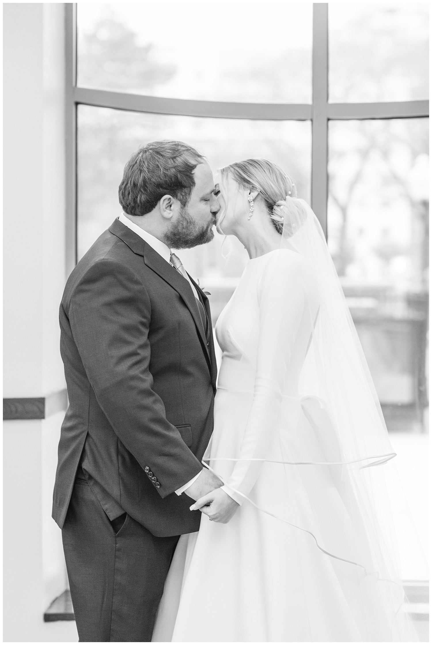 bride and groom kissing in front of big windows in Columbus, Ohio
