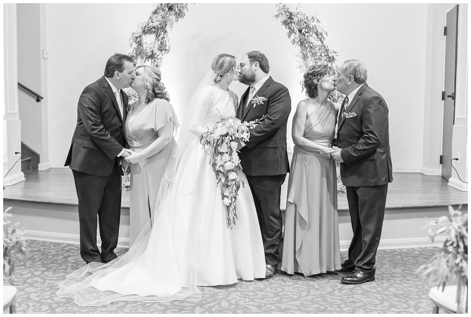 bride and groom and both sets of parents all kissing at the same time